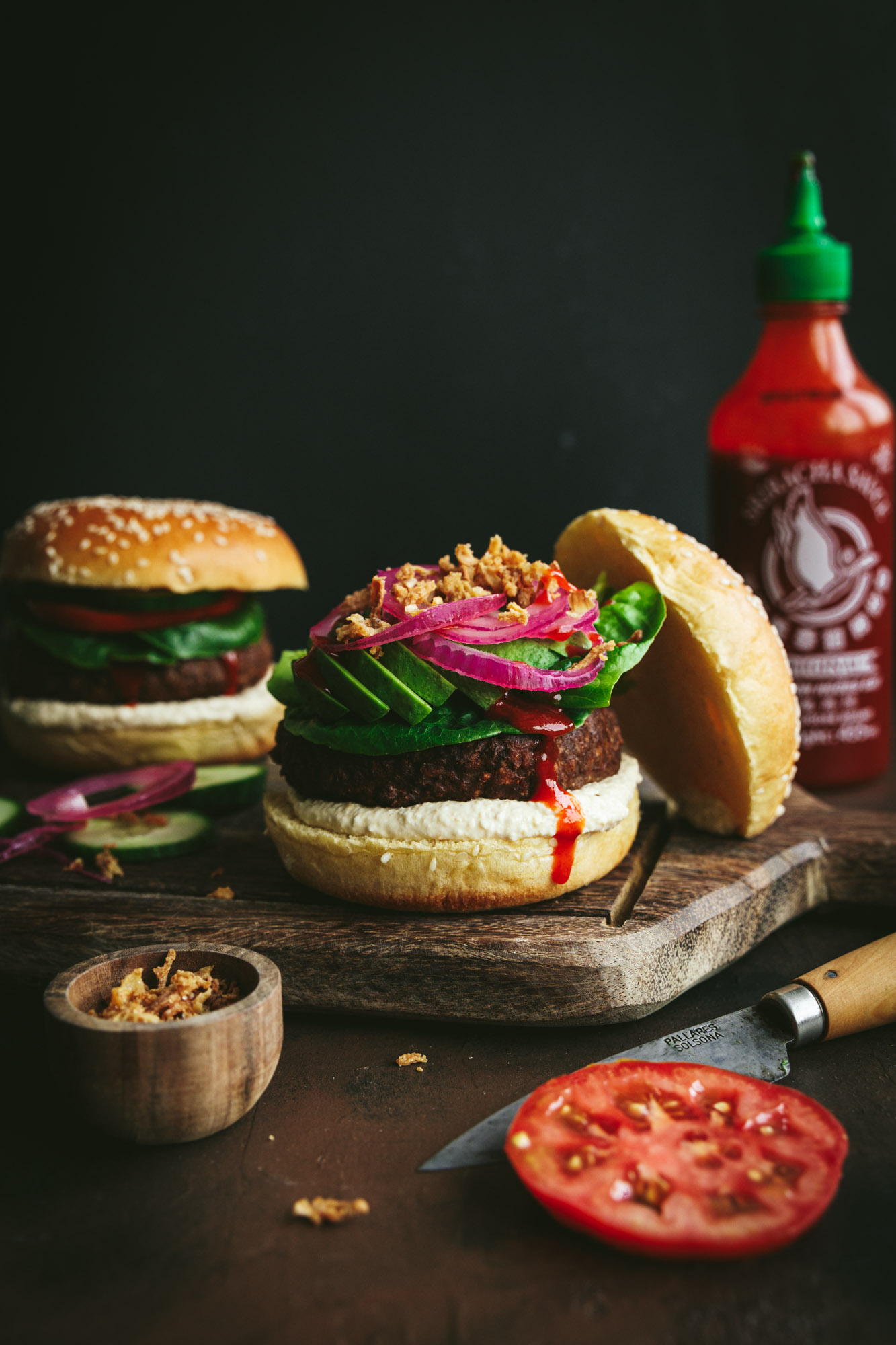 Two plant based burgers served on a wooden cutting board