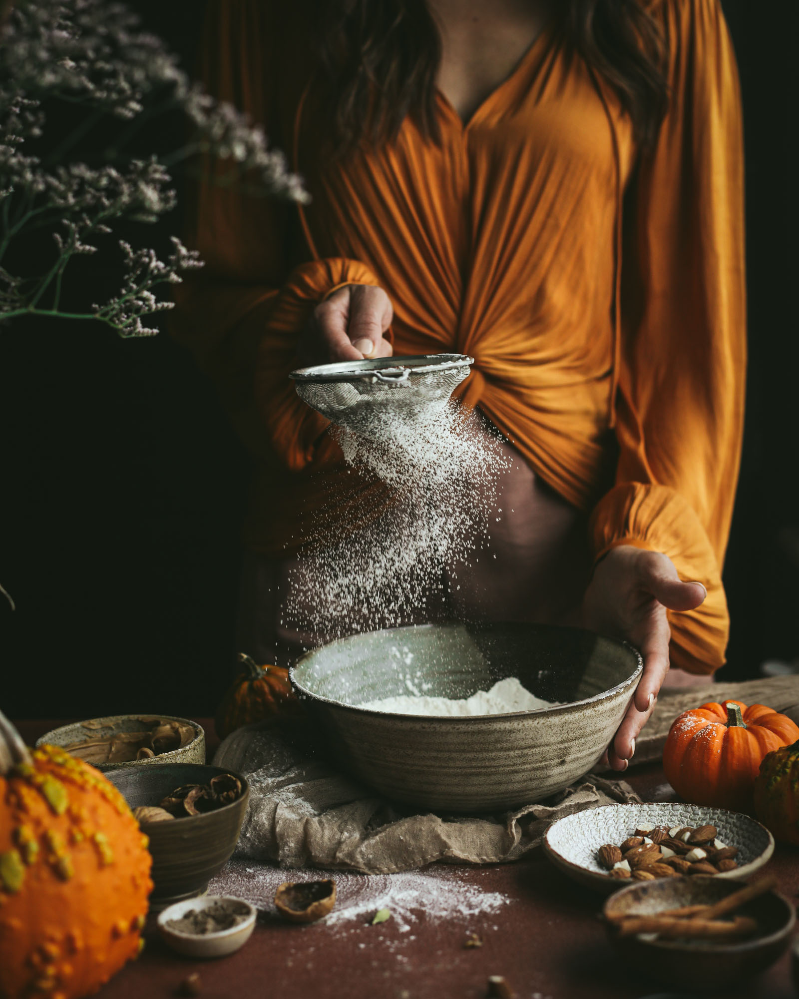 woman sifting flower whilst making a healthy recipe