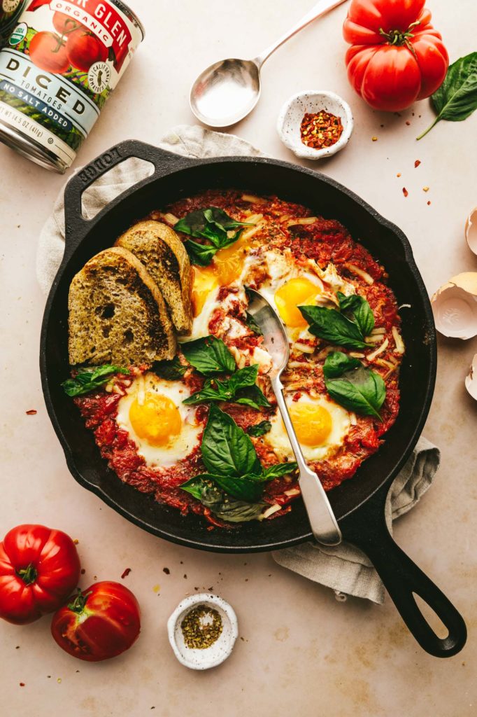 Italian Eggs served on a cast iron skillet with remaining ingredients laying around.